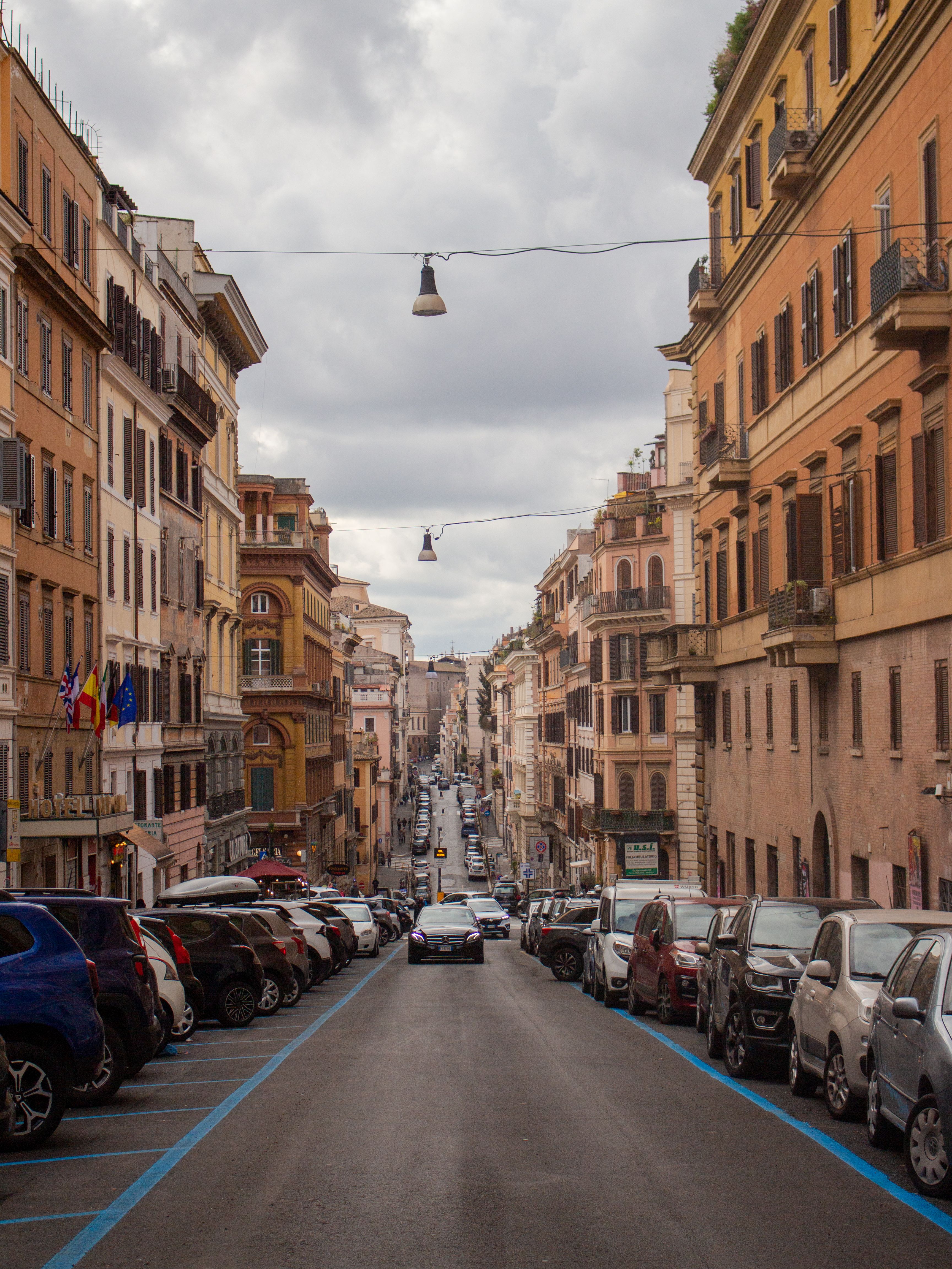 Discover the bustling streets of Rome, Italy with parked cars lining an historic urban landscape.