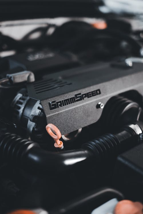 A close up of a car engine with a small orange wire