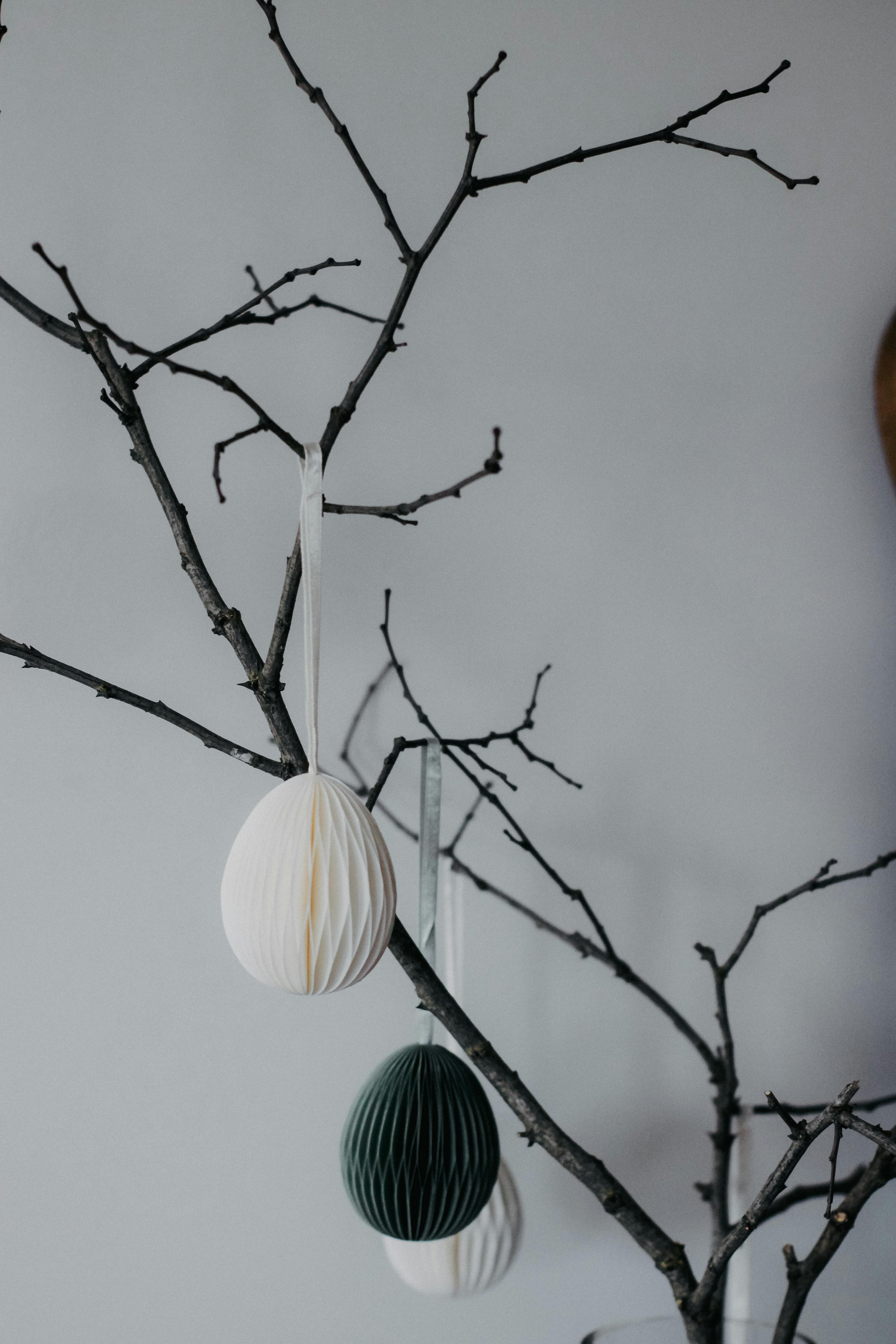 Elegant Christmas decorations with paper ornaments on barren branches, minimalist style for modern interiors.