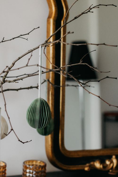 Free Stylish hanging paper ornament on branches against a decorative mirror indoors. Stock Photo
