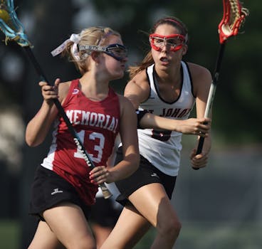 Two female lacrosse players in action outdoors during a competitive game.
