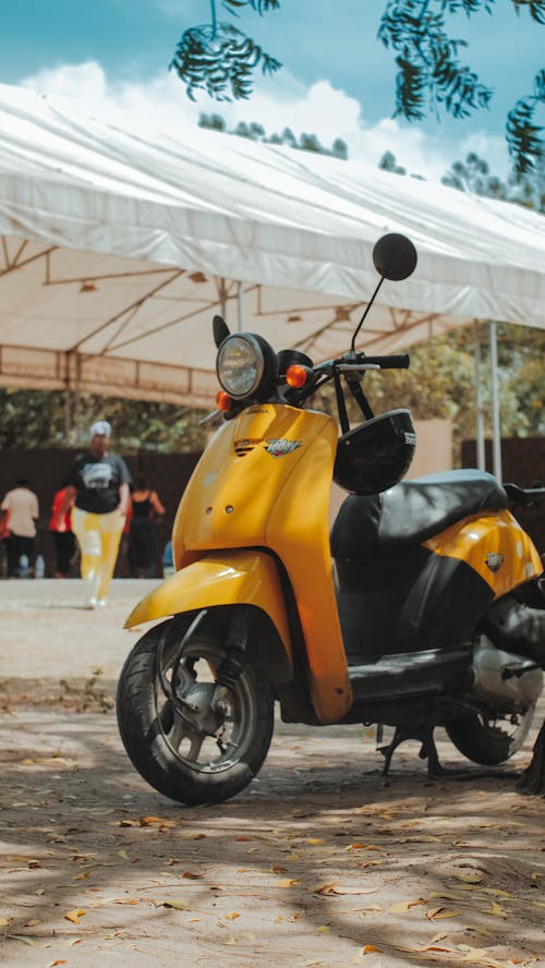 A yellow scooter parked in front of a white tent
