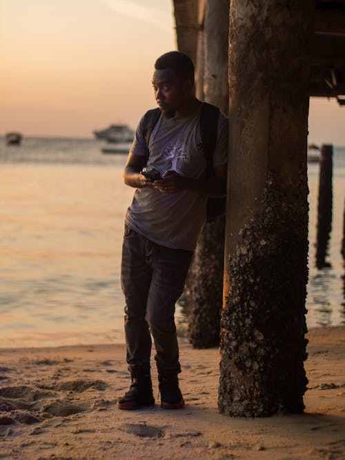 A man standing on the beach looking at his phone