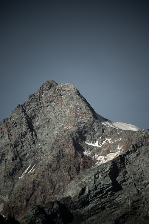 Free A striking view of a snow-dusted mountain peak set against a clear blue sky, showcasing rugged terrain and natural beauty. Stock Photo