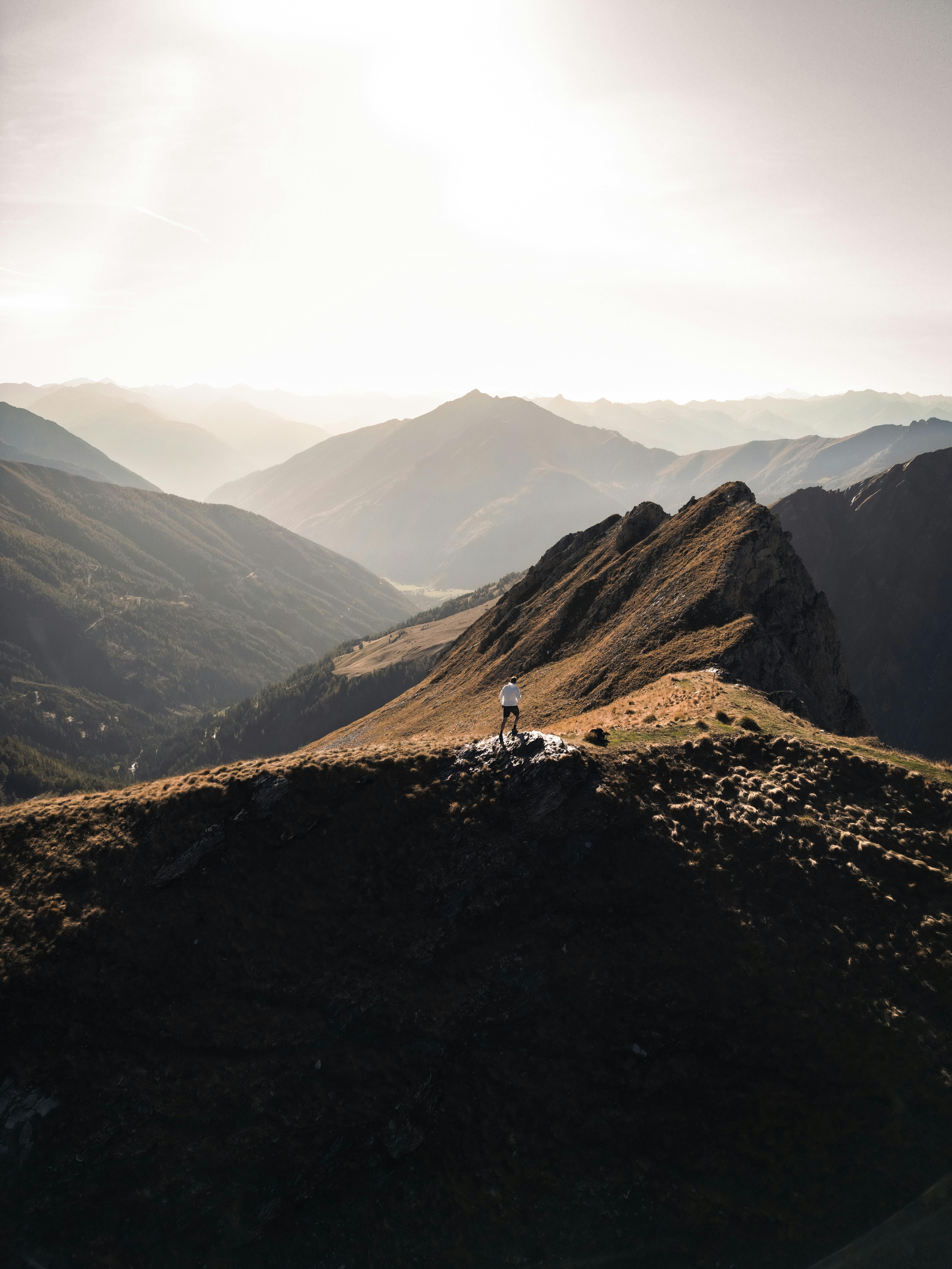 A breathtaking aerial view of a lone hiker standing amidst stunning mountain scenery.