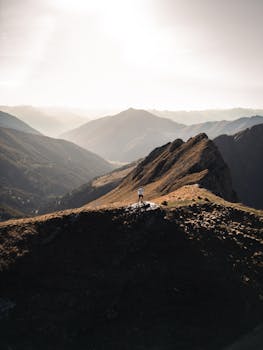 A breathtaking aerial view of a lone hiker standing amidst stunning mountain scenery.