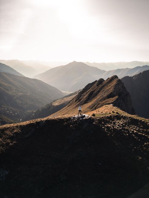 A breathtaking aerial view of a lone hiker standing amidst stunning mountain scenery.