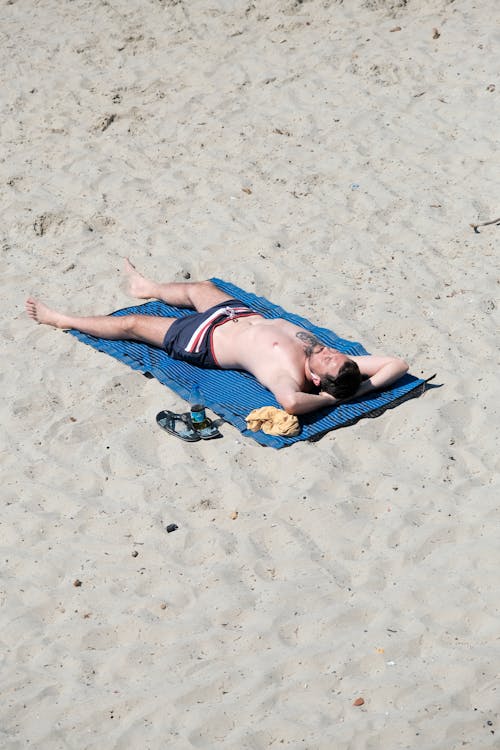 澄んだ青空の下、砂浜で一人日光浴をする人