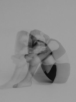 Black and white double exposure of a woman in sportswear, seated and contemplative.