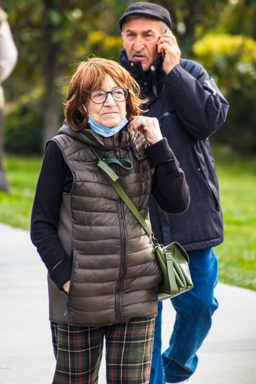 Free Elderly couple walking in a park on a cold winter day, woman wears eyeglasses and a jacket. Stock Photo