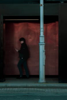 A shadowy figure walks by a streetlight at night, emphasizing urban solitude.