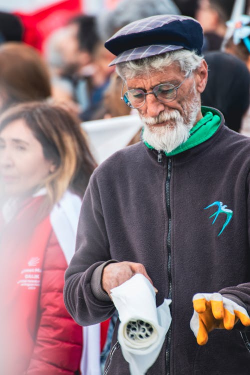 A man with a beard and glasses holding a bottle