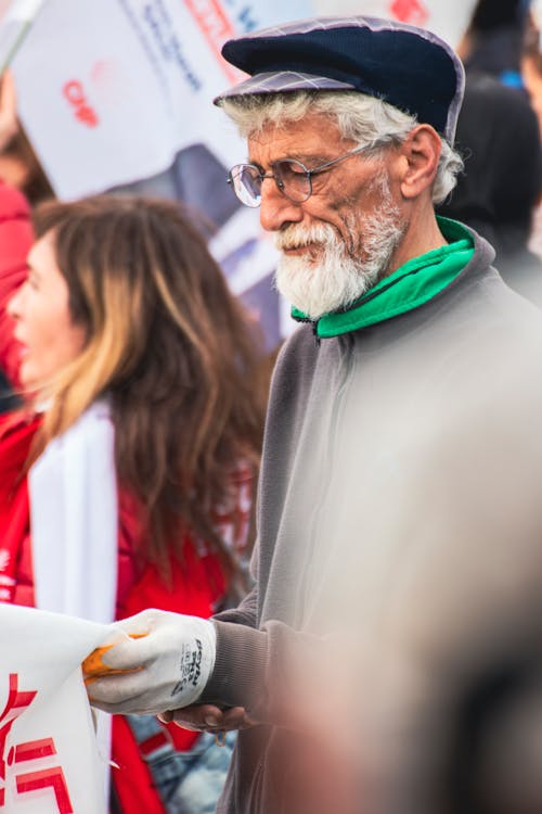 An older man with a beard and glasses holding a sign