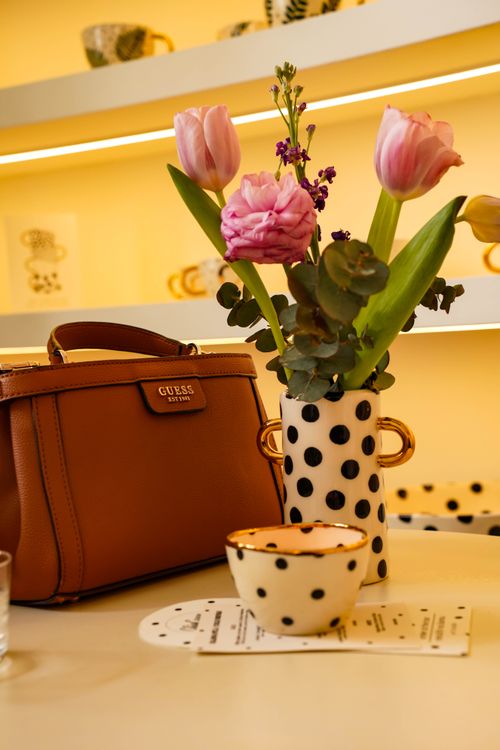 Free Elegant floral arrangement in a polka dot vase with a fashionable bag and cup on a table in Zagreb. Stock Photo