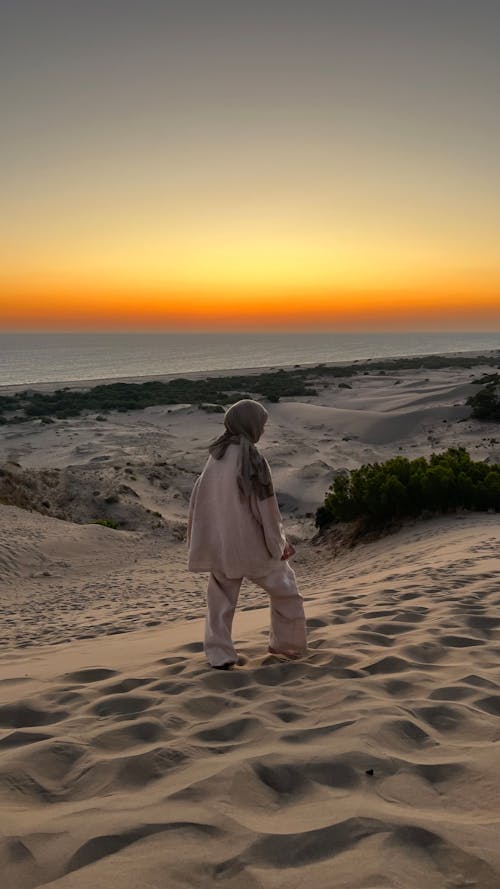 Photo of a Woman Walking on a Beach at Sunset 