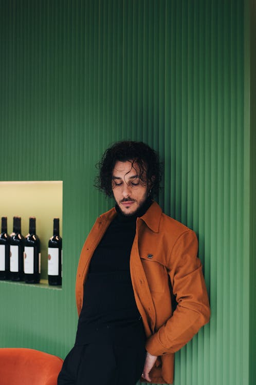 Fashionable Man Standing against a Green Wall 