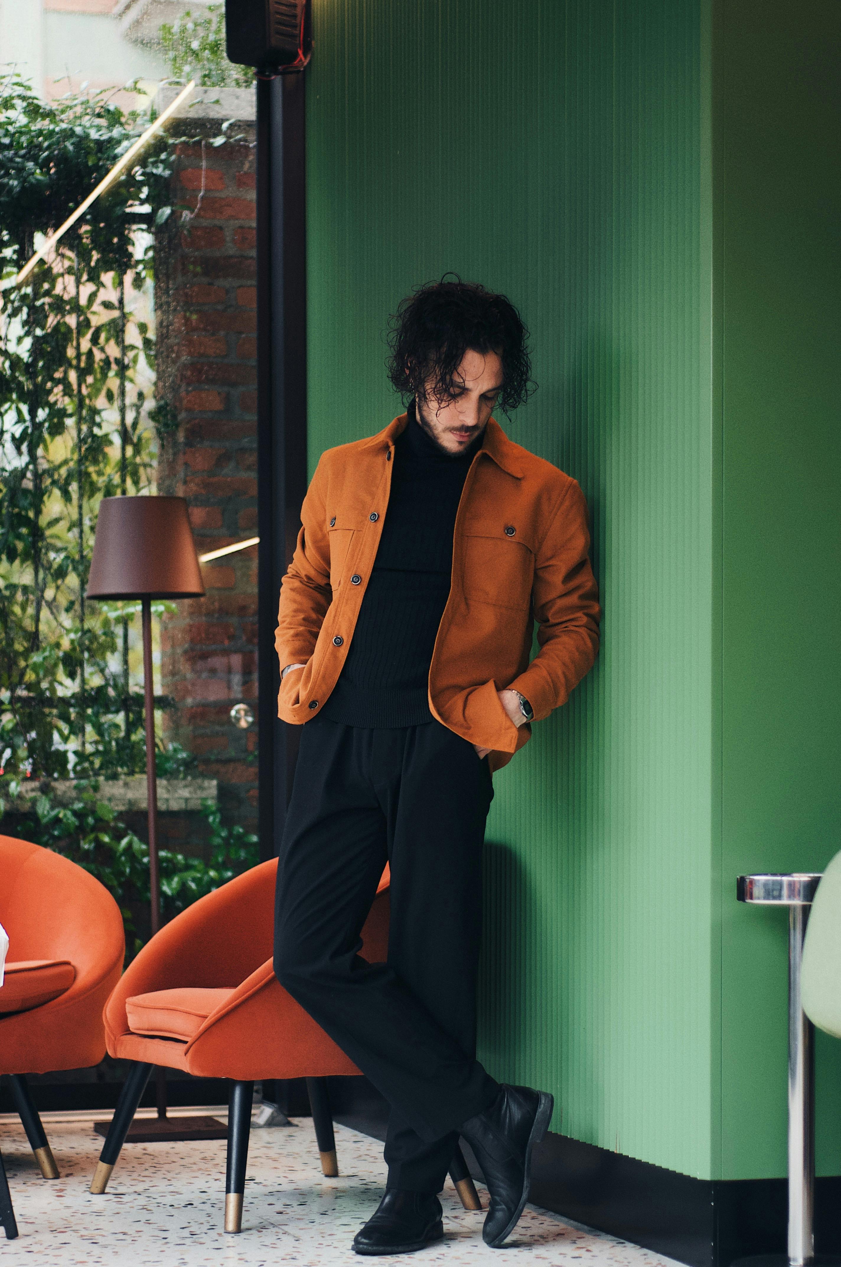 Fashionable man in a cozy cafe with a stylish green interior. Perfect for modern lifestyle themes.