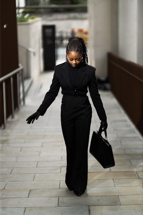 A woman in a black suit walking down a hallway