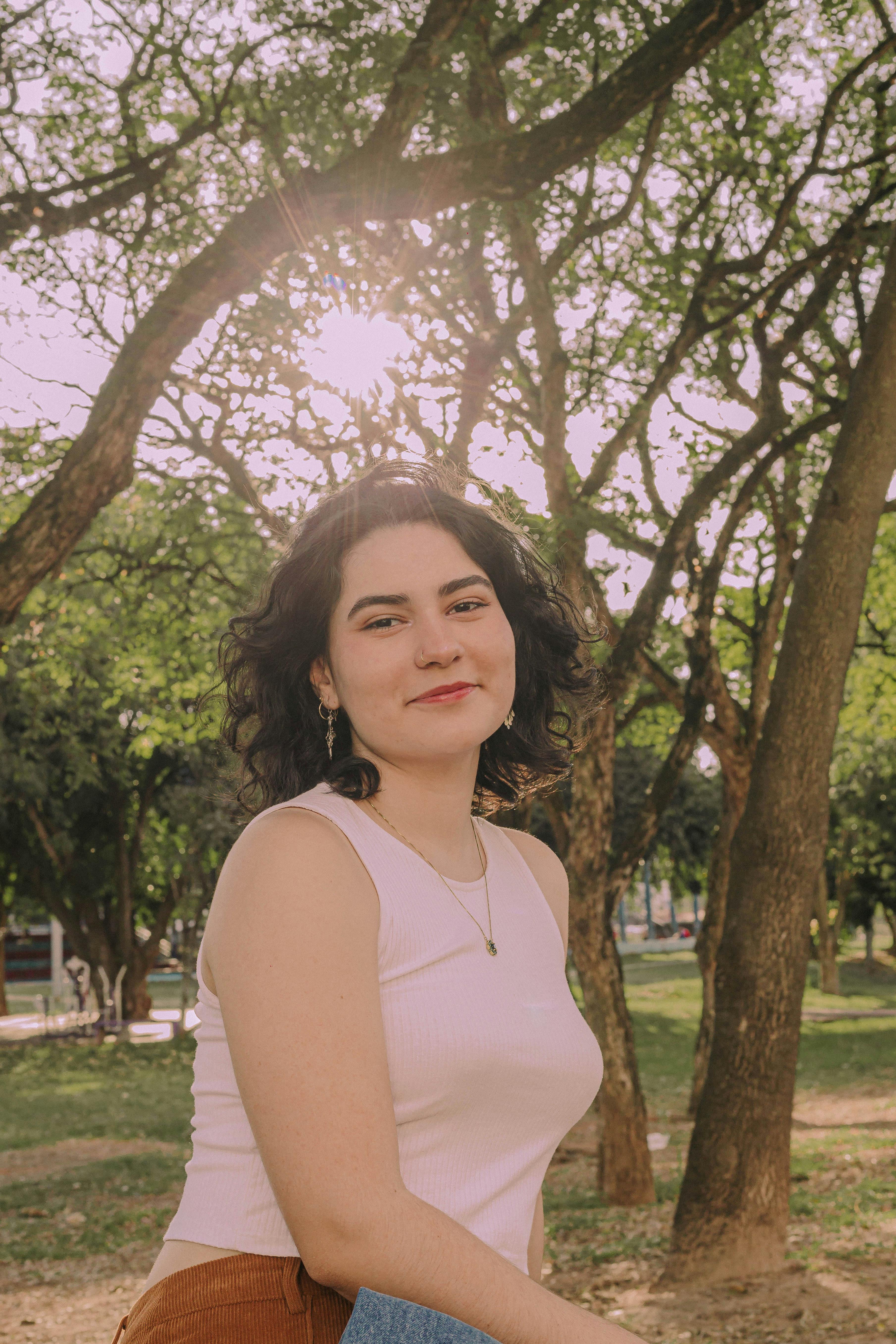 A young woman smiling in a sunlit park in Presidente Prudente, Brazil.