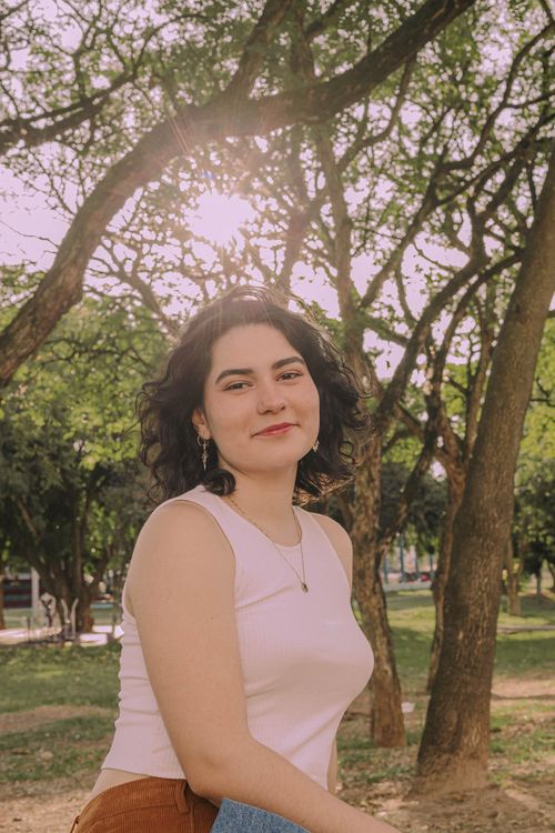 Free A young woman smiling in a sunlit park in Presidente Prudente, Brazil. Stock Photo