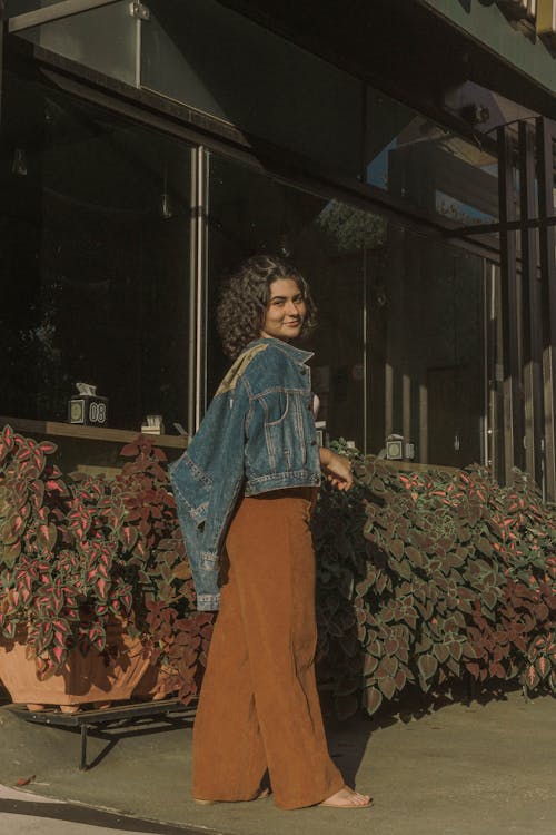 A woman in a brown pantsuit and a denim jacket