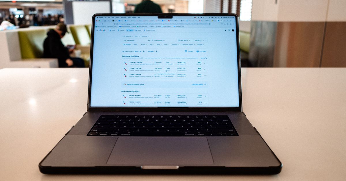 A laptop open to a flight search in an airport lounge, illustrating whether incognito mode gets you cheaper flights