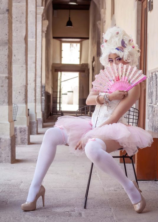 A Woman Wearing a Costume and a Wig Sitting on a Chair · Free Stock Photo