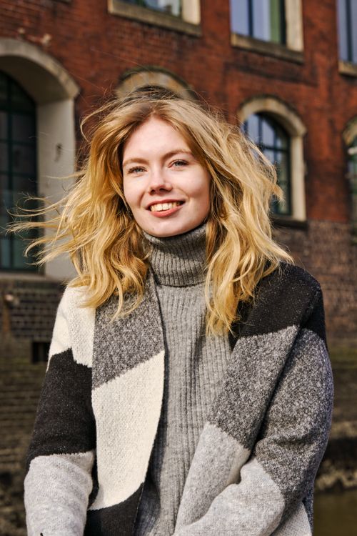 Free Stylish young woman with blonde hair smiling in a windy urban setting in Hamburg. Stock Photo