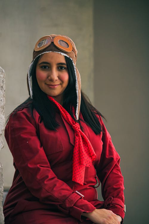 A woman wearing a red shirt and a pilot hat