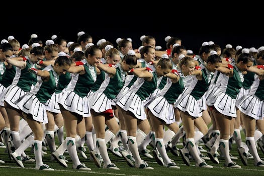 A team of cheerleaders in green uniforms performing energetically outdoors.