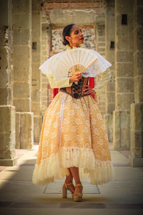 A woman in a traditional mexican dress holding a fan