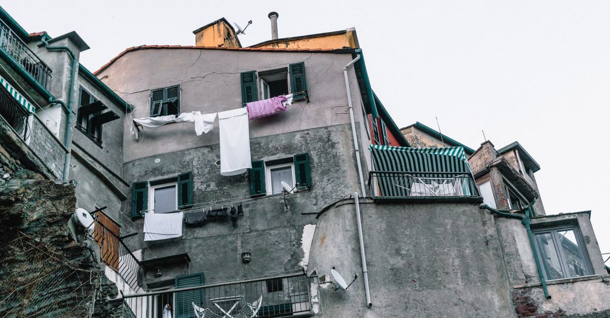 a quiet cobblestone street with laundry hanging overhead and a lone cat sitting on the steps in a European town