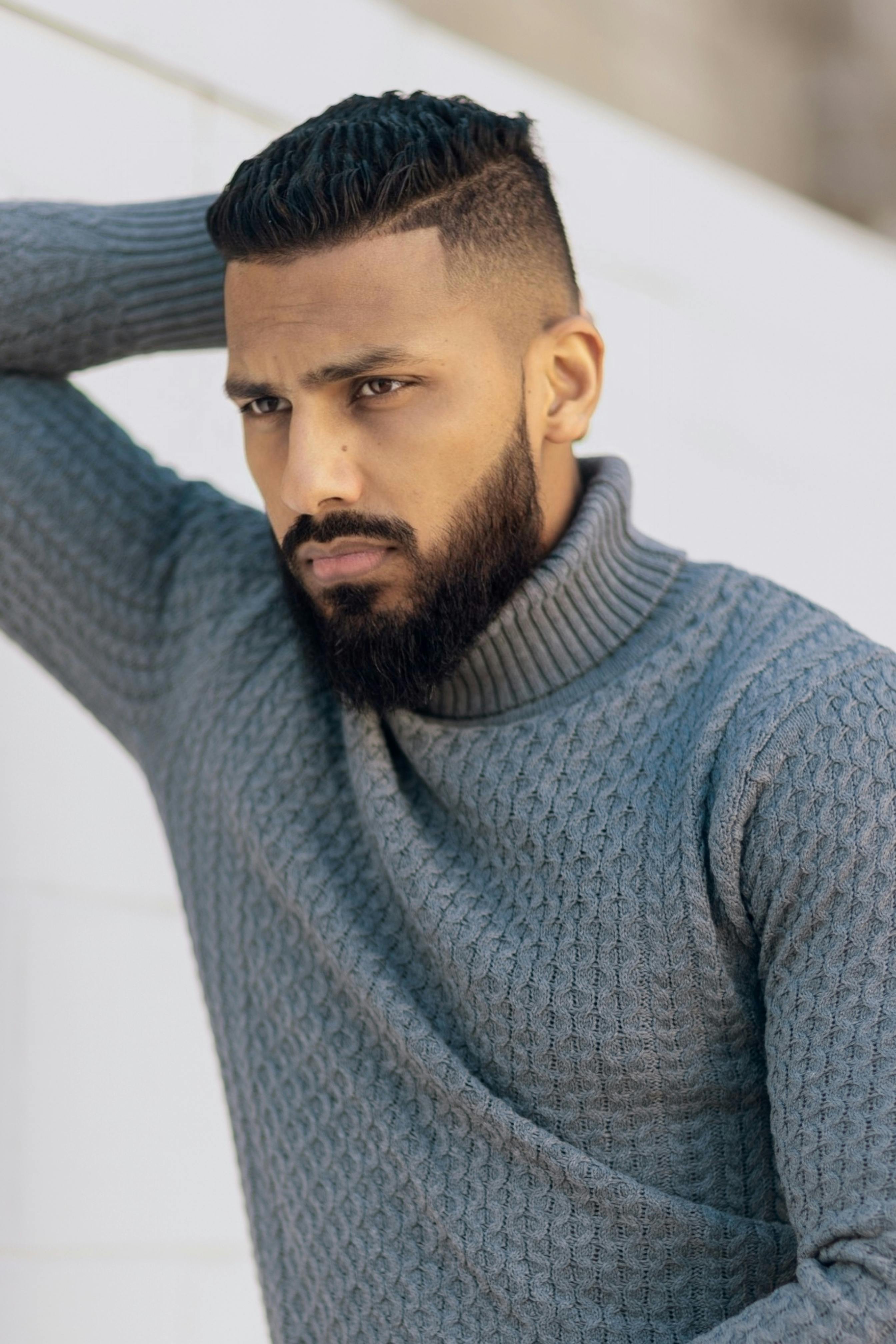 Portrait of a man with a beard wearing a gray turtleneck sweater.