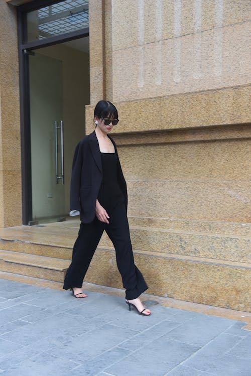 A woman in black jumpsuit walking down the street