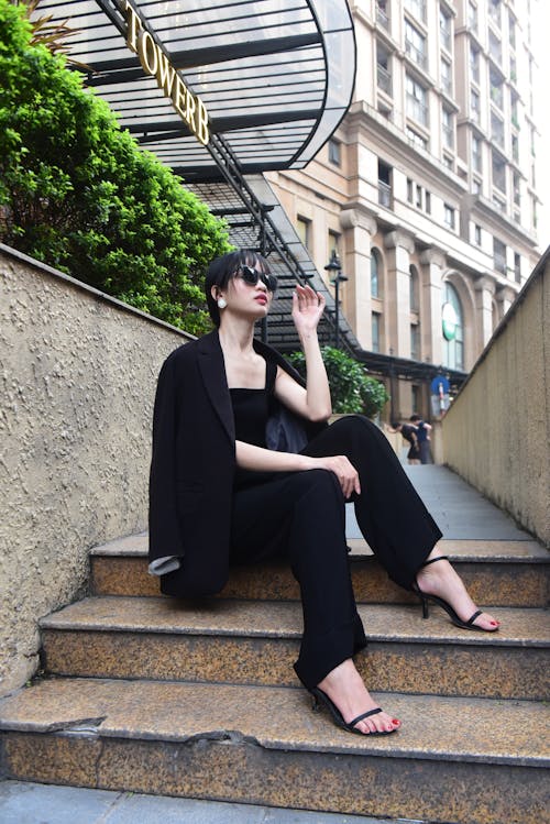 A woman in black suit sitting on steps