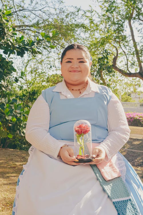 A woman in a blue dress holding a flower