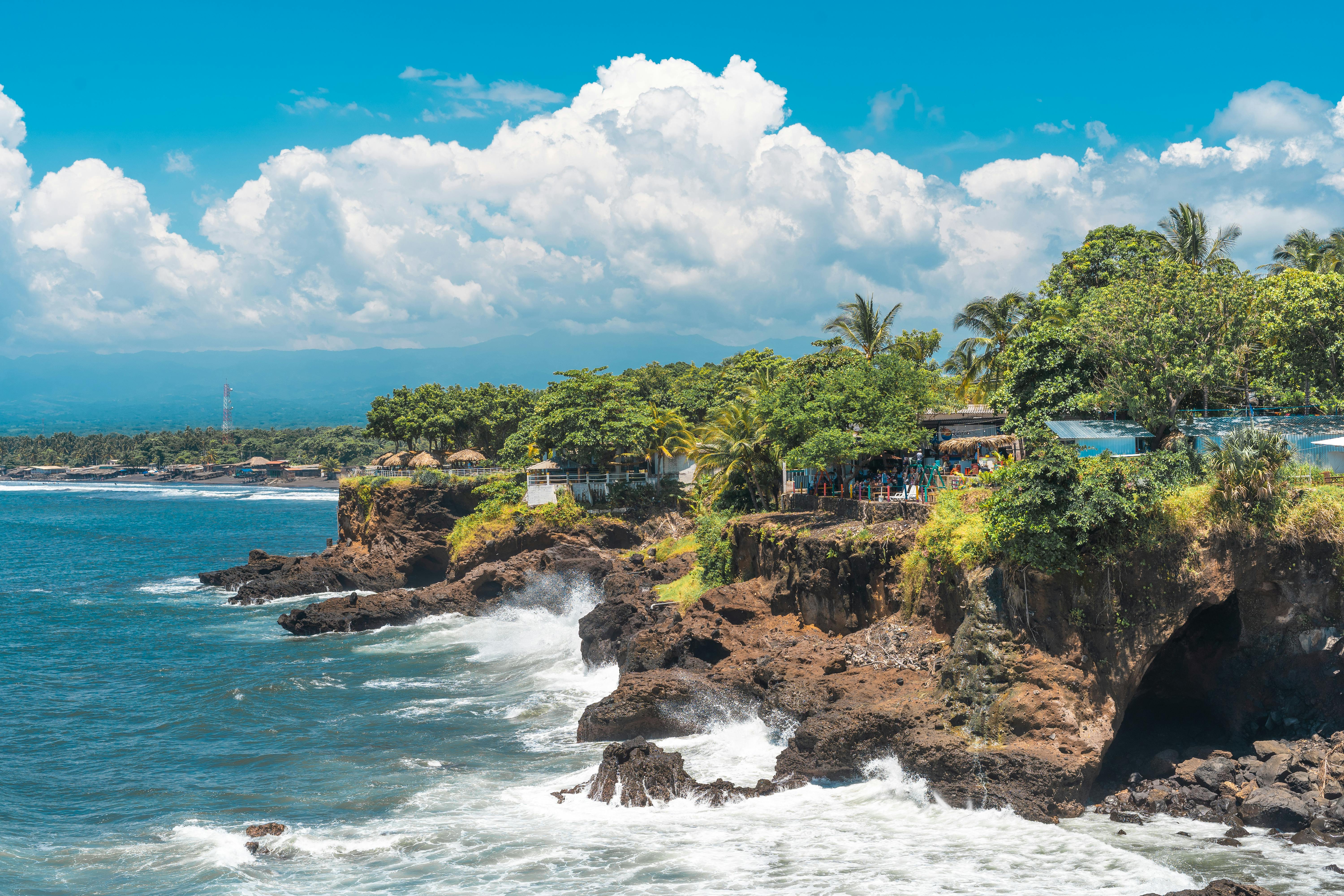 Scenic tropical seascape with dramatic cliffs and turquoise ocean waves crashing along a lush coastline.