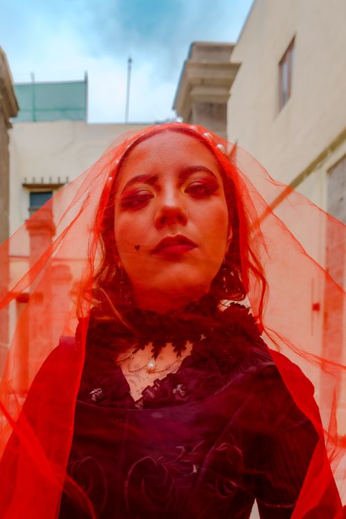 Free Captivating portrait of a woman in a red veil with a dramatic background. Evokes mystery and elegance. Stock Photo