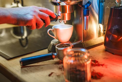Free A barista uses an espresso machine to brew a fresh cup of coffee in a cozy café setting. Stock Photo