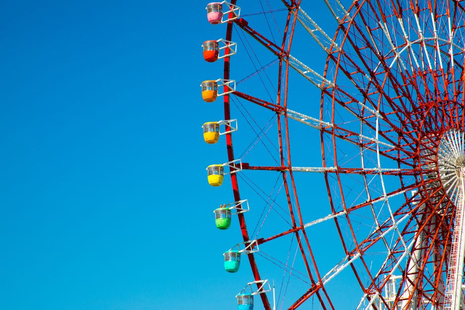 A colorful ferris wheel with a clear blue sky background, perfect for themes of fun and entertainment.