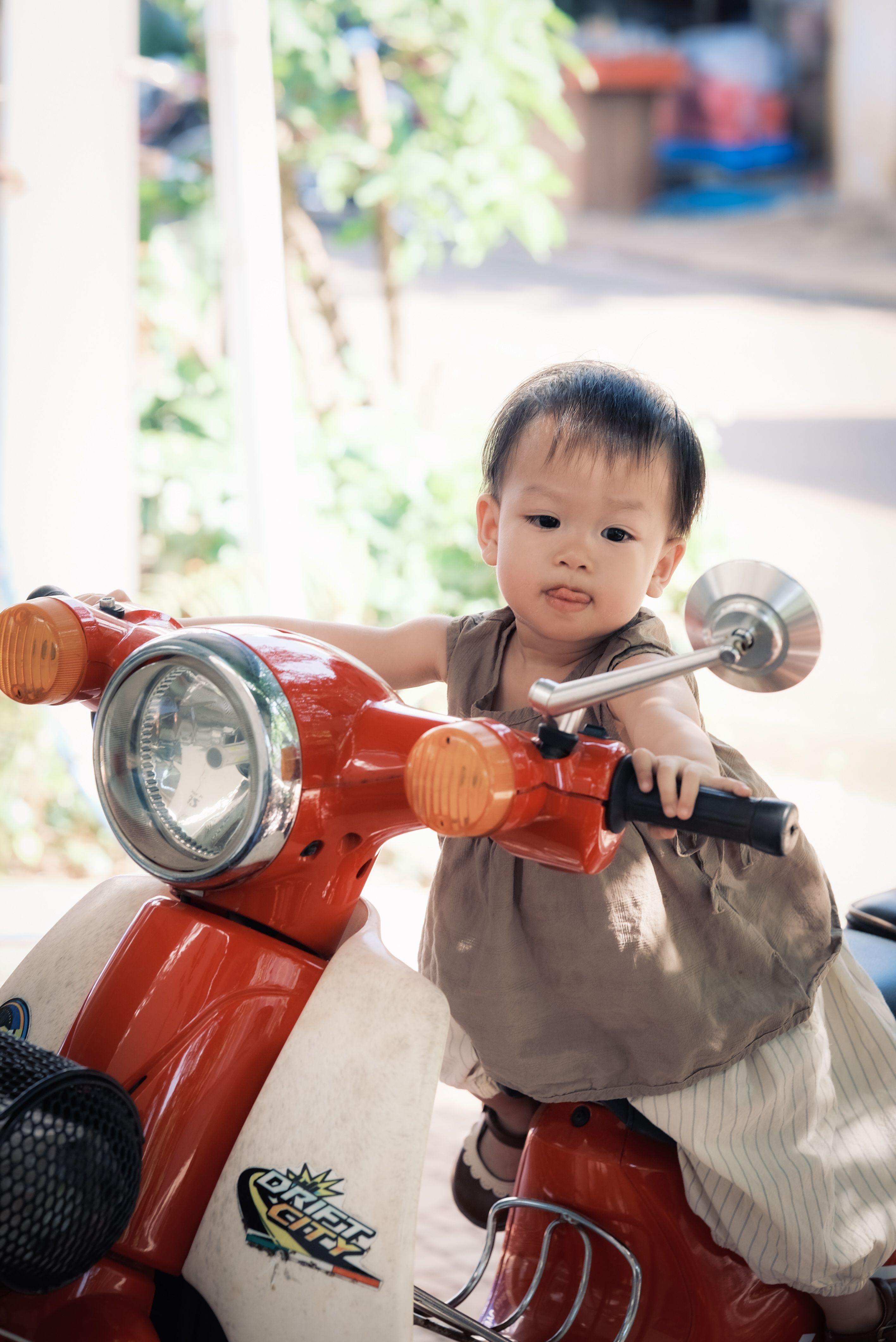 A small child sitting on the back of a red moped · Free Stock Photo