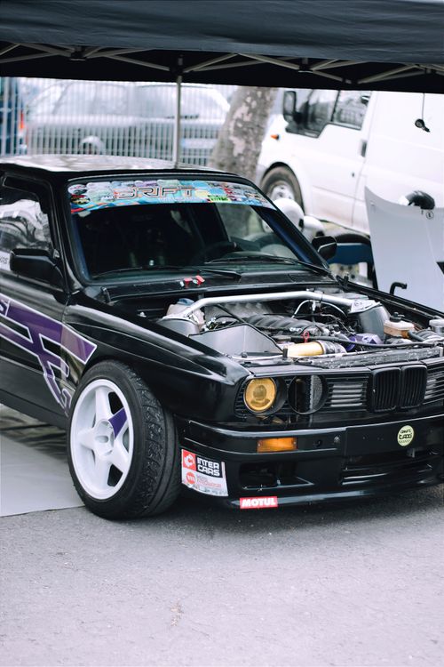 Free Black sports car with custom headlights and exposed engine parked under a tent in Hungary. Stock Photo