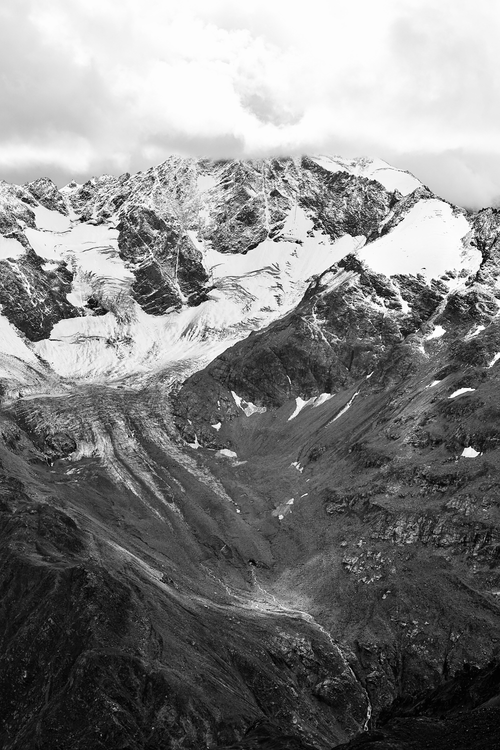 Free A striking black and white image of a snow-covered mountain range under cloudy skies. Stock Photo