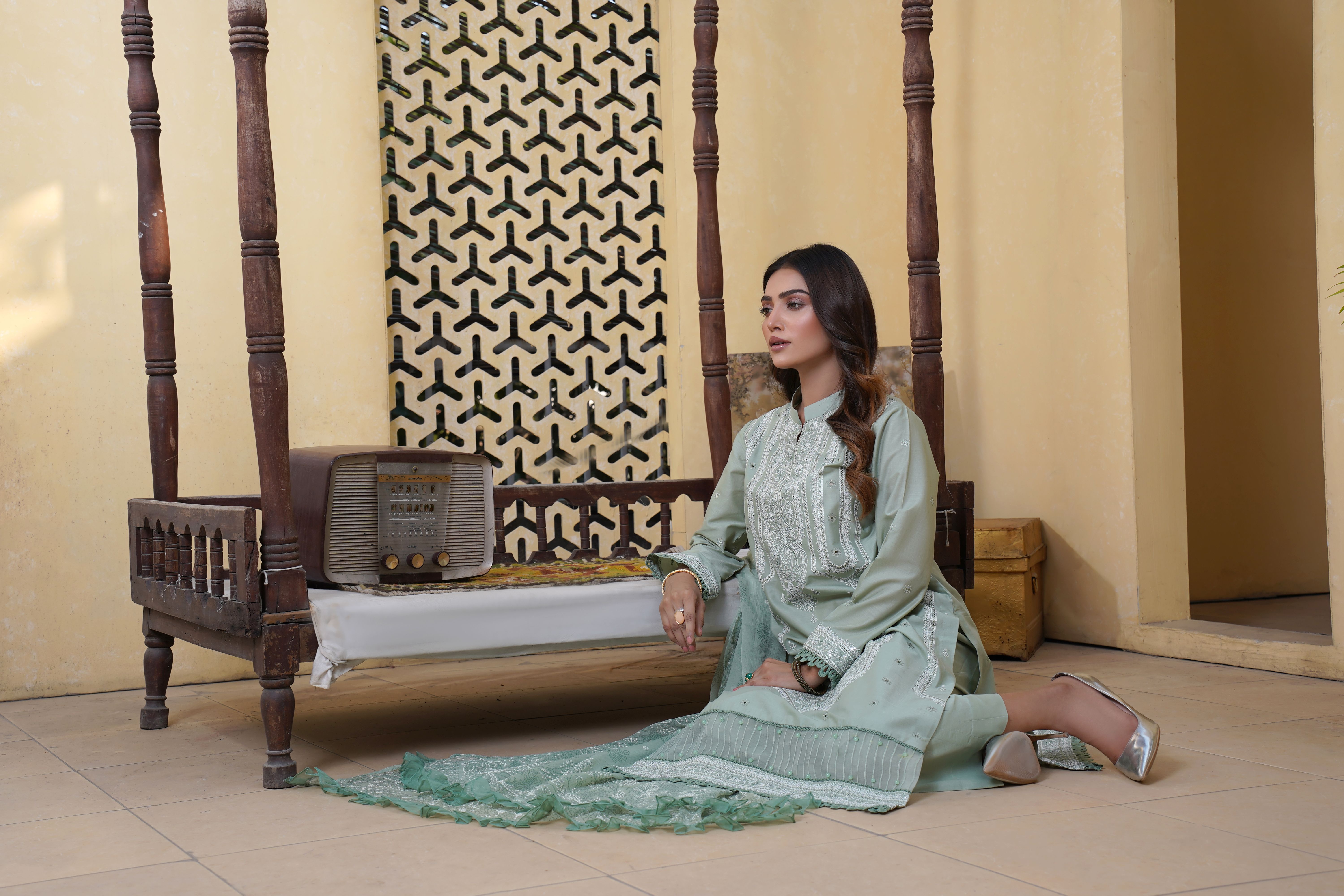 A woman elegantly dressed in a Daman embroidered cross slub digital printed lawn, showcasing intricate embroidery and vibrant colors.