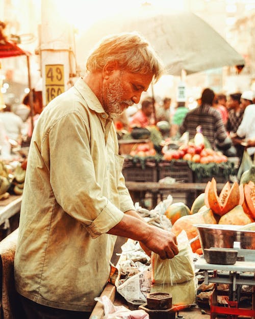 A man is standing in front of a fruit stand