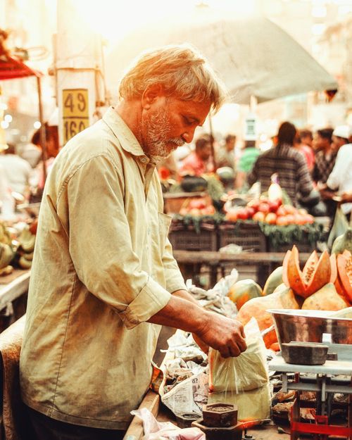 Free An elderly vendor selling fresh produce at a vibrant outdoor market. Stock Photo