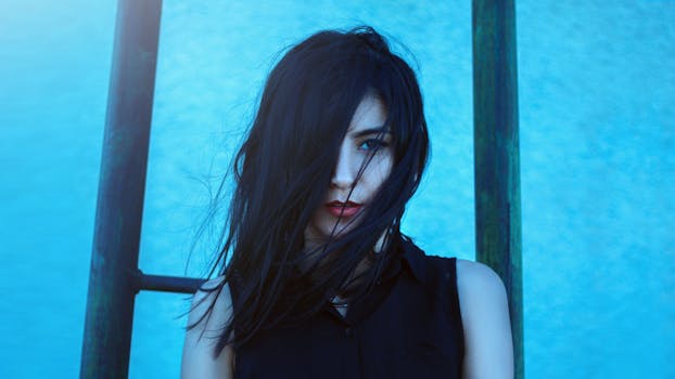 这幅肖像引人注目，描绘了一位头发飘逸的女性，背景是充满活力的蓝色