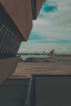 A plane parked on the tarmac at an urban airport seen through building architecture.