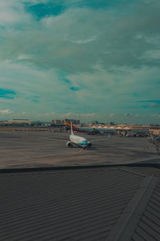 A commercial airplane taxiing on a runway at an urban airport with a vast sky view.
