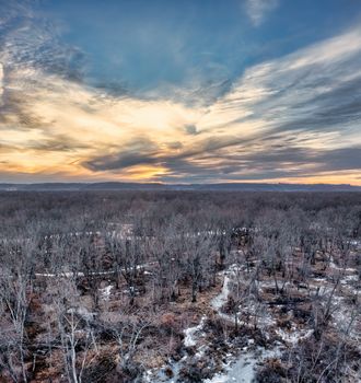 Aerial view of a winter landscape in Nelson, WI, showcasing a peaceful sunset over a bare forest.